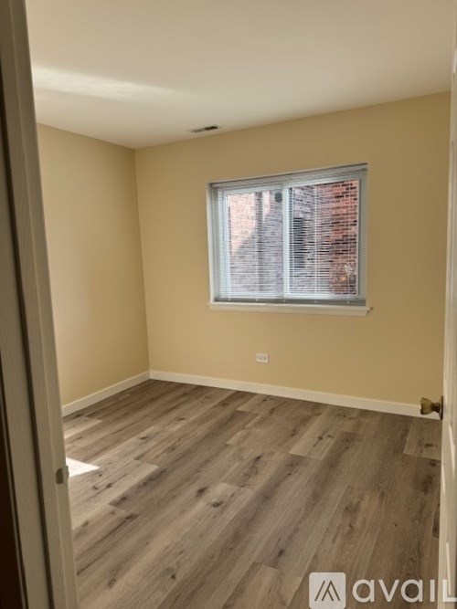 A room with wooden flooring and a window with blinds.