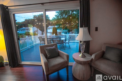 A living room with a chair and a table with a lamp on it.