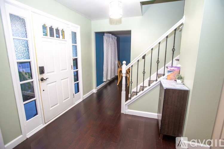 A hallway with a staircase and a white door with a glass panel.