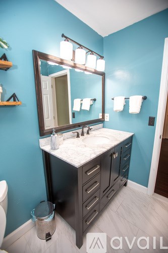 A bathroom with blue walls and a marble counter.