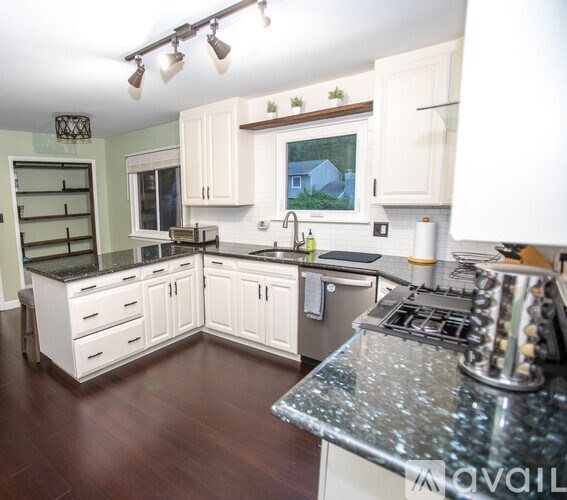 A kitchen with white cabinets and a granite countertop.