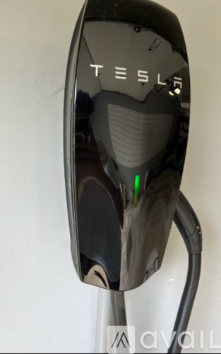 A Tesla charging station is plugged in and charging an electric vehicle.