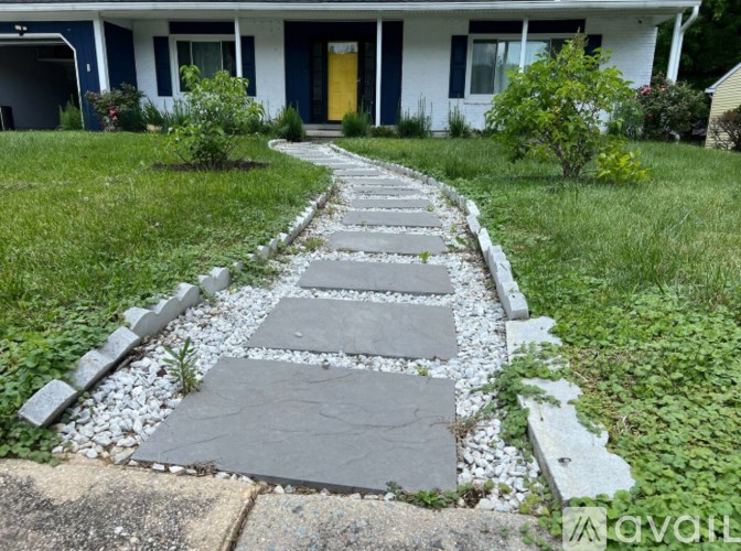 A white house with a yellow door and a stone pathway leading to it.