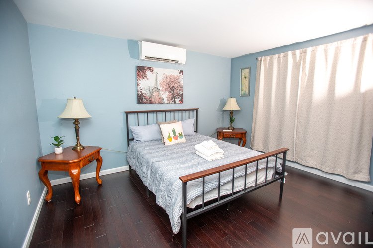 A bedroom with a bed, nightstands, and a painting on the wall.