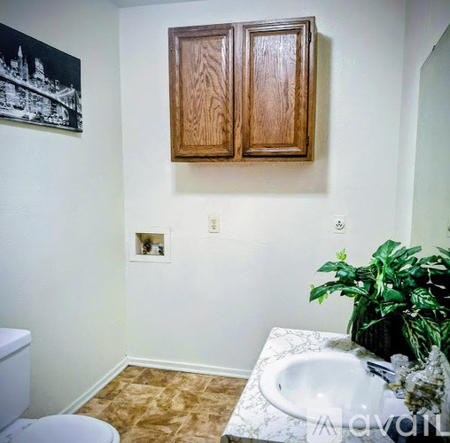 A bathroom with a toilet, sink, and a plant.