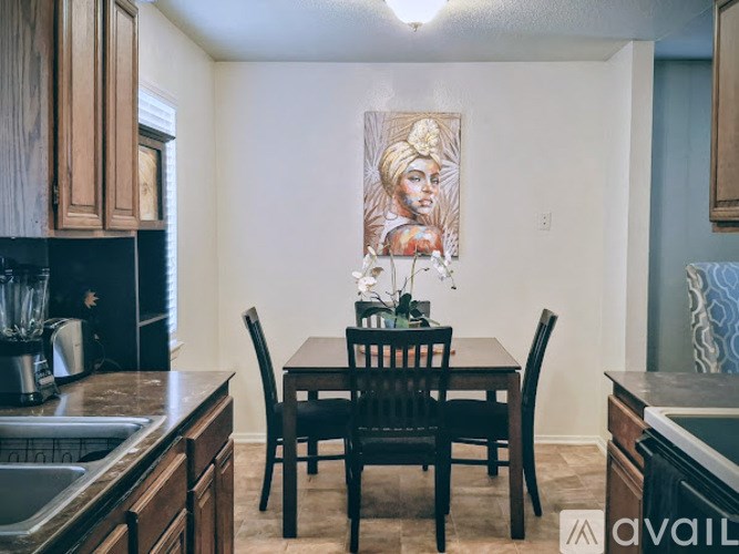 A kitchen with a table and chairs and a painting on the wall.