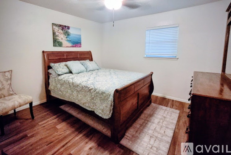 A bedroom with a bed, chair, and rug.