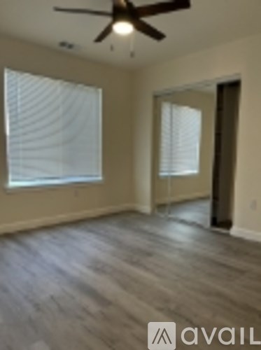 A room with a ceiling fan and wood flooring.