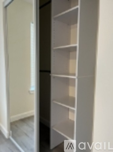 A white shelving unit with several shelves is in a room.