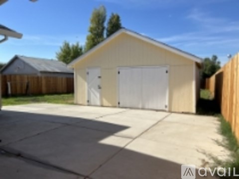 A garage with a white door is situated in a backyard.