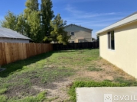 A backyard with a wooden fence and a house in the background.