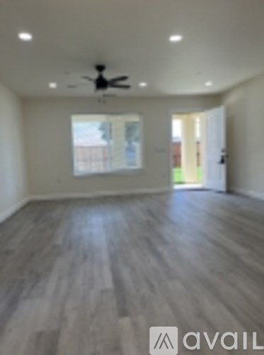 A room with a fan and wooden flooring.