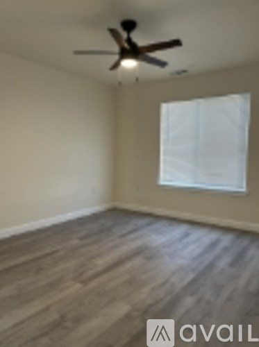 A room with a ceiling fan and a window with white curtains.