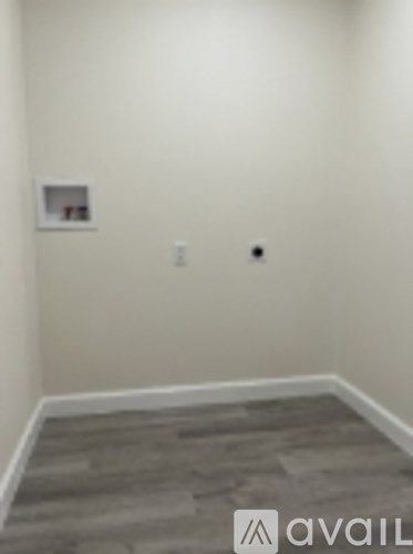 A room with a grey carpet and a white wall.