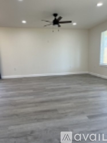 A room with a ceiling fan and wooden flooring.