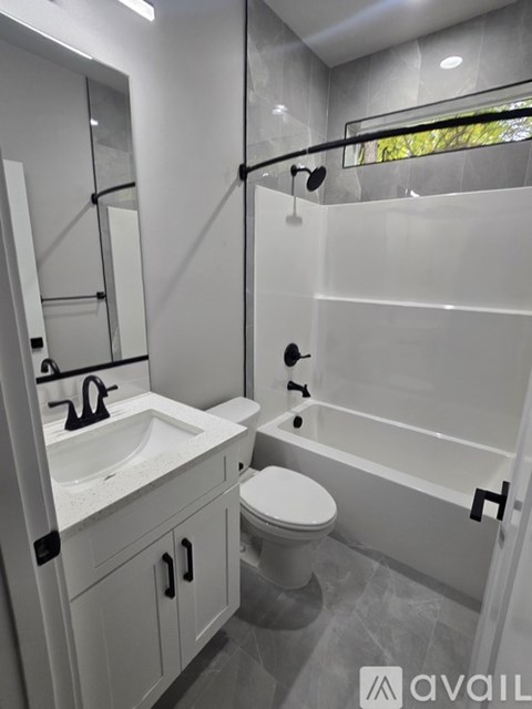 A modern bathroom with a white toilet, sink, and bathtub.