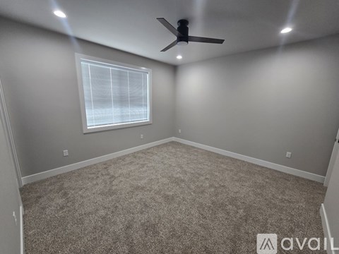 A room with a carpeted floor and a ceiling fan.