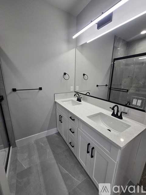 A bathroom with a sink, mirror, and a shower.