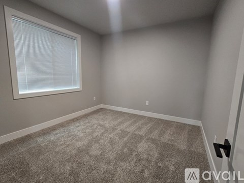 A room with a carpeted floor and a window with blinds.