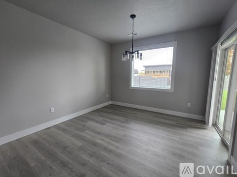 A room with wooden flooring and a window overlooking a fence.