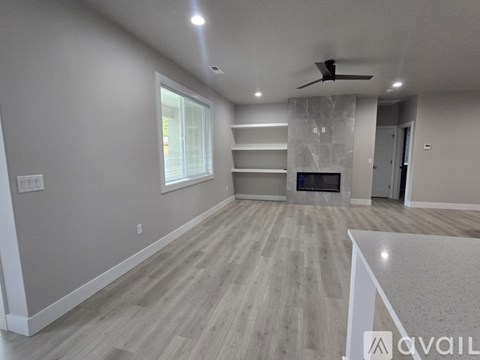 A spacious living room with a fireplace and a ceiling fan.