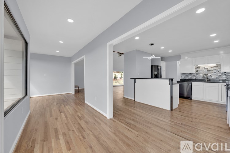 A modern kitchen with wooden floors and white walls.