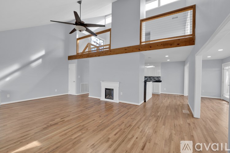 A spacious living room with a fireplace and a fan.