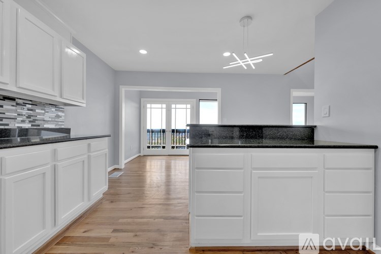A kitchen with white cabinets and a black countertop.