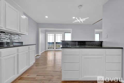 A kitchen with white cabinets and a black countertop.