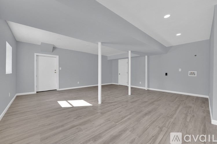 A spacious room with wooden flooring and white walls.