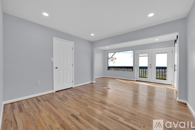 A spacious room with wooden flooring and white walls.