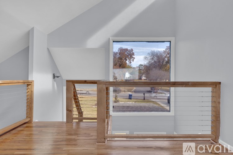 A room with wooden floors and a large window showing an outdoor scene.