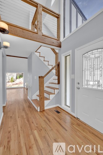 A wooden staircase with a white railing leads to a second floor.