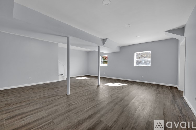 A spacious room with wooden flooring and white walls.