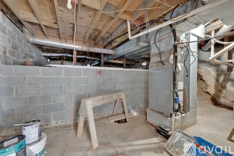 A room under construction with exposed pipes and wooden support beams.