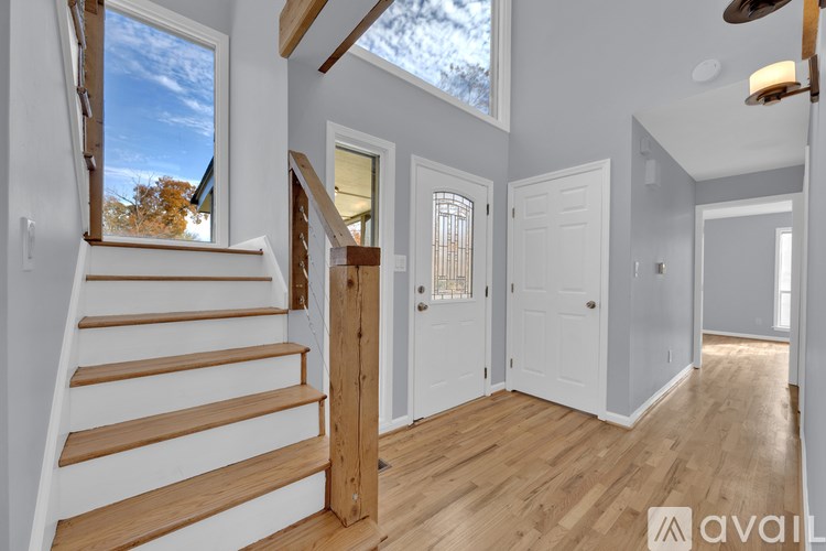 A wooden staircase with white risers leads to a bright room with a skylight.