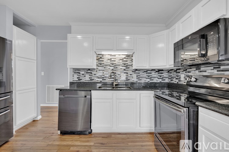 A kitchen with white cabinets and a black and white tiled backsplash.