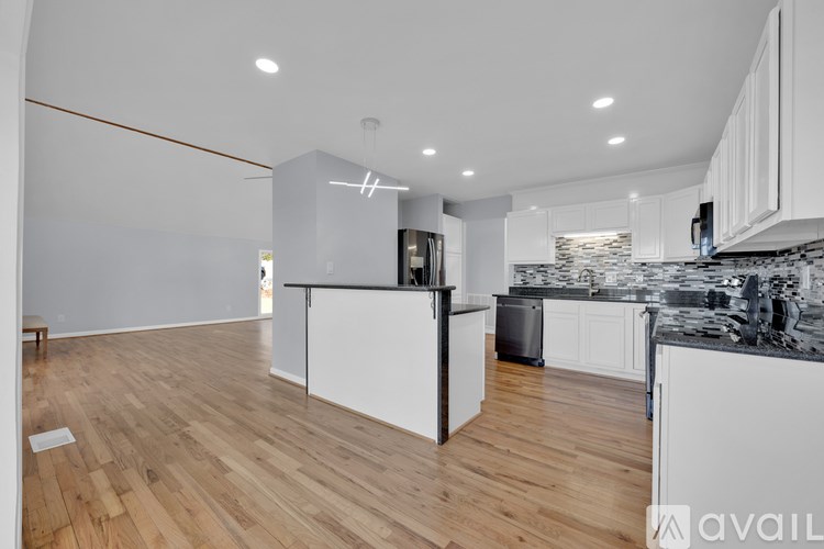 A modern kitchen with wooden floors and white cabinets.