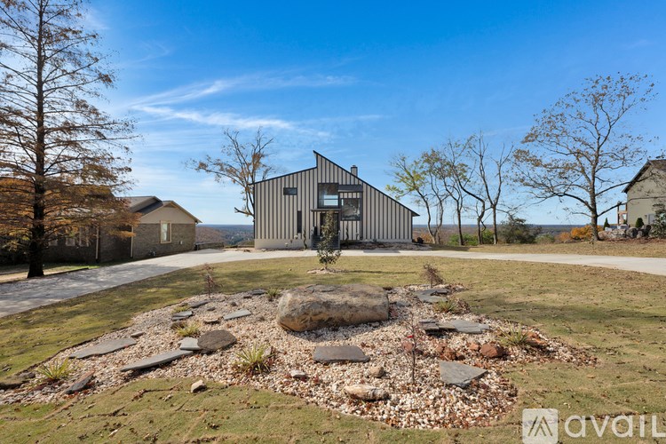 A modern house with a large front yard and a stone pathway leading to it.