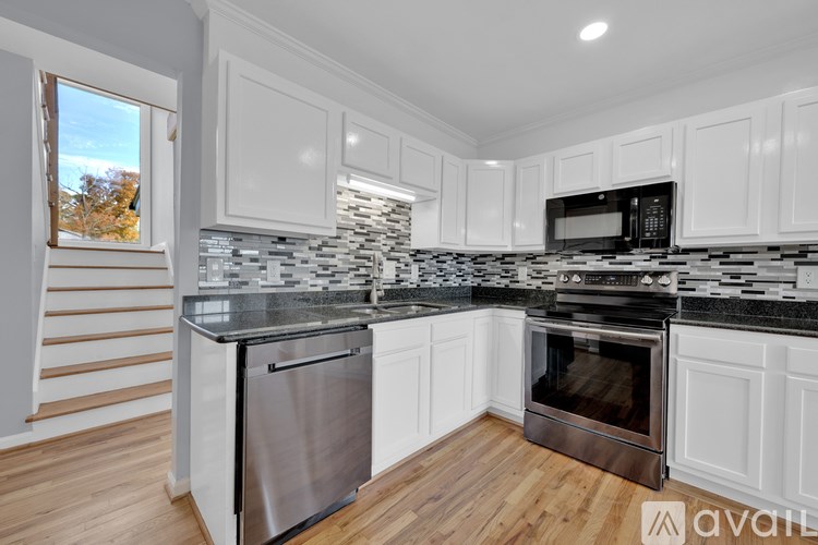 A kitchen with white cabinets and a black and white tiled backsplash.
