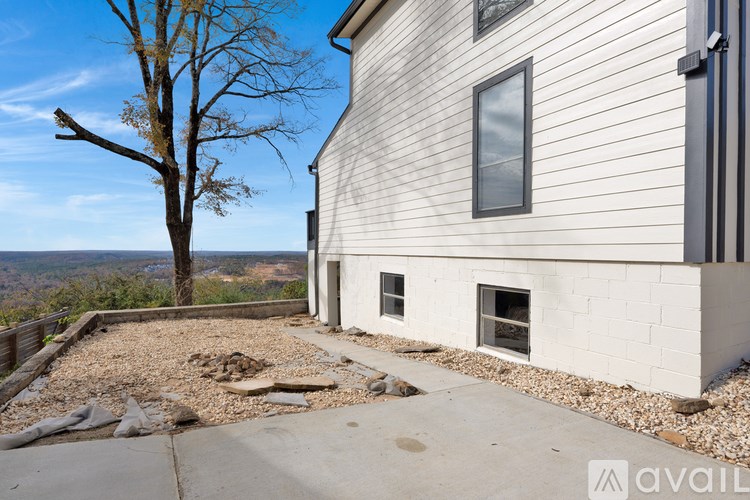 A house with a white exterior and a large tree in the background.
