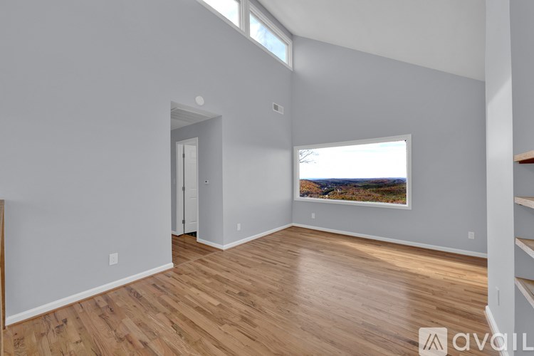 A spacious room with wooden flooring and a large window.