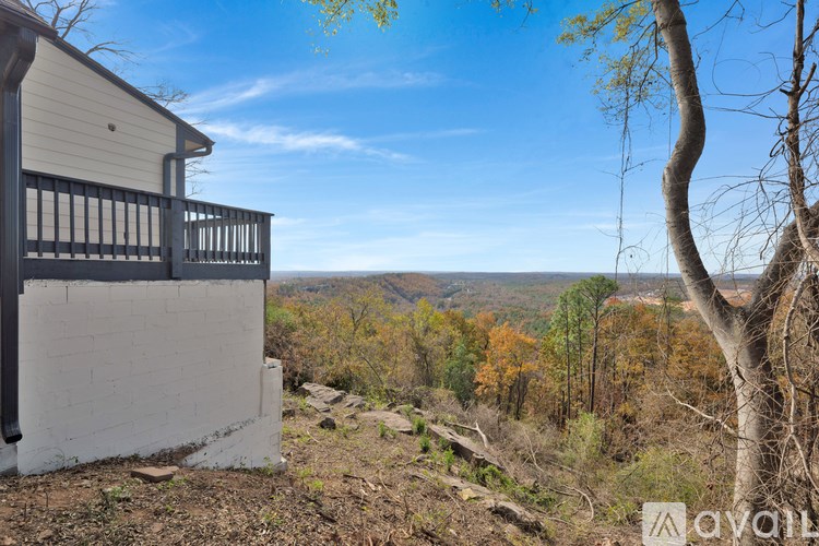 A house with a balcony overlooks a view of a forest.