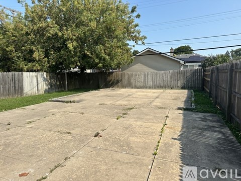 A backyard with a concrete slab and a wooden fence.