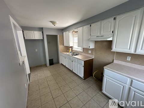 A kitchen with white cabinets and a tiled floor.