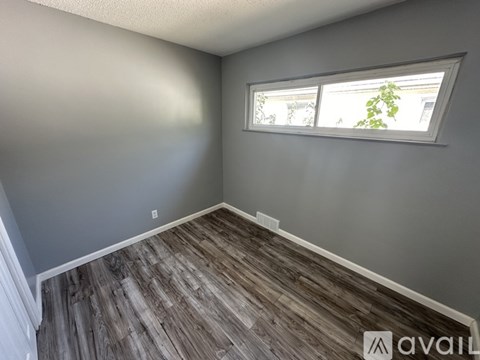 A room with a window and wooden flooring is available for rent.