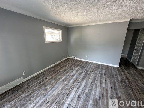 A room with grey walls and wooden flooring is available for rent.