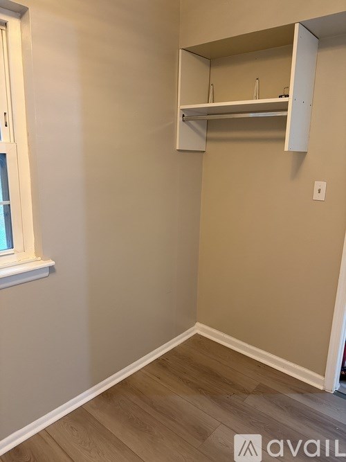 A white shelf is mounted on a wall above a wooden floor.