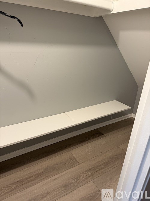 A corner of a room with a wooden floor and a white wall.