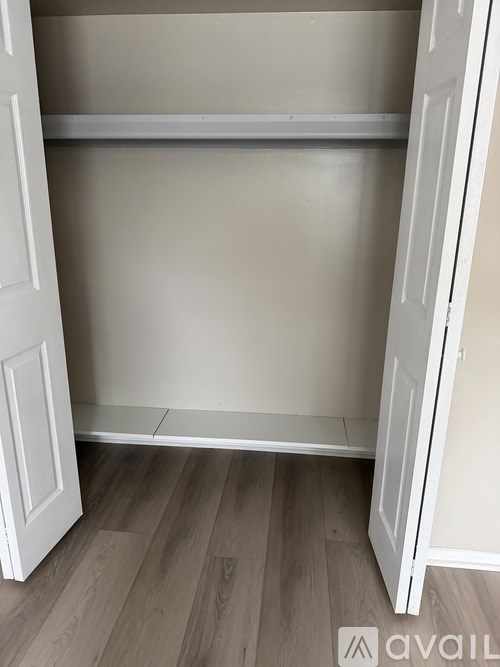 A white closet with a wooden floor and a shelf.